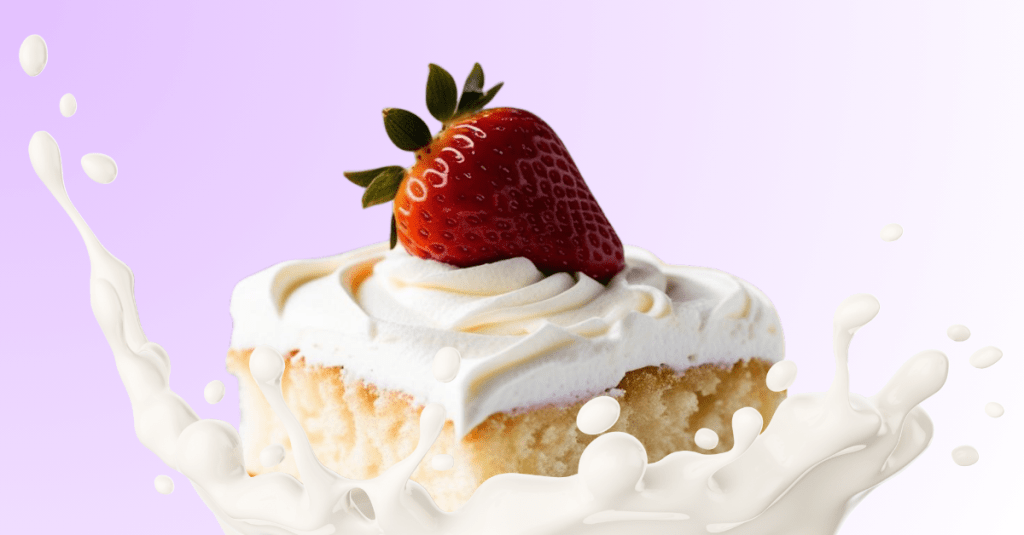 A squared tres leches cake slice with a single strawberry on top in a splash of milk